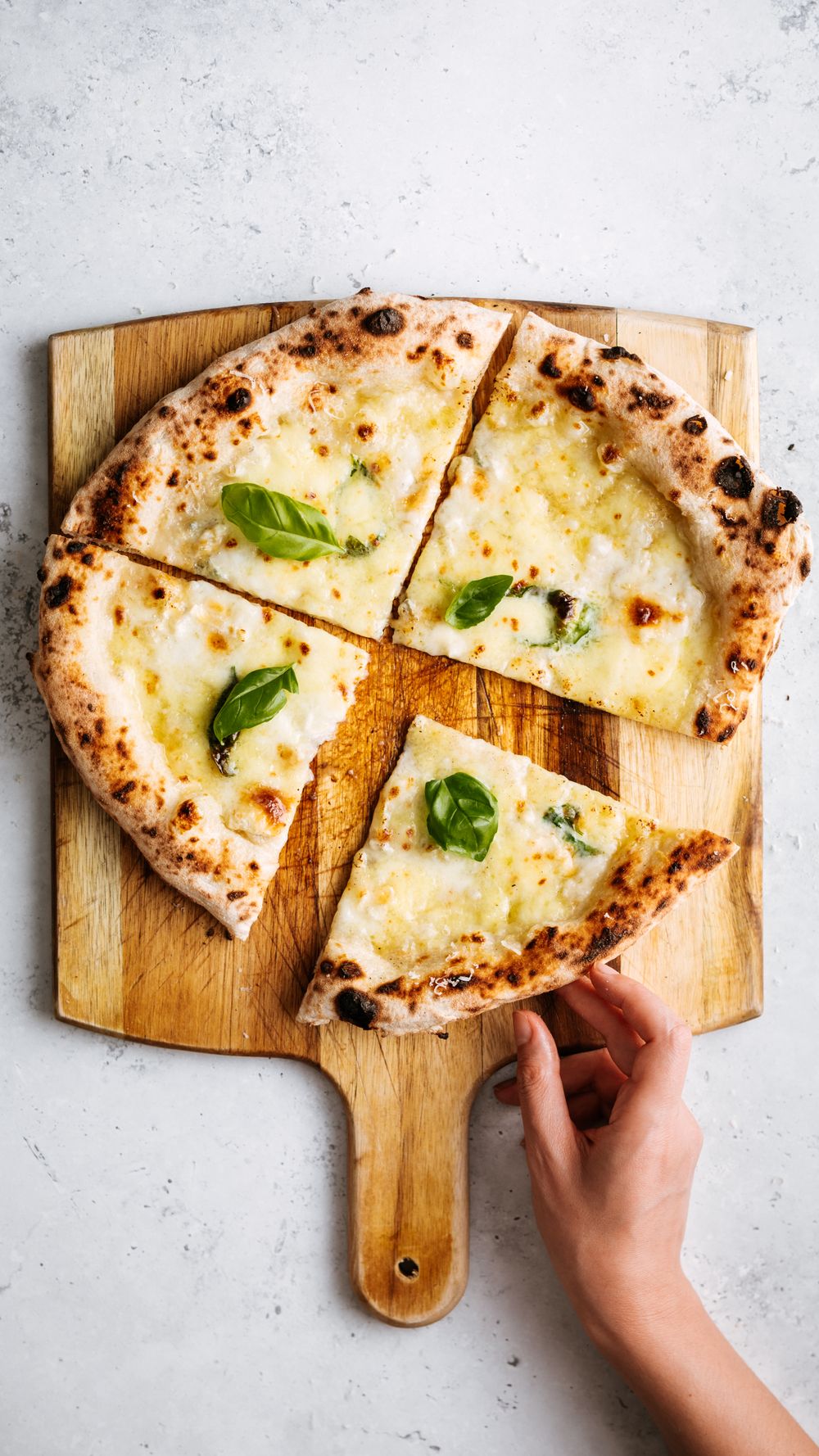 Pizza au fromage fondant découpée sur une planche